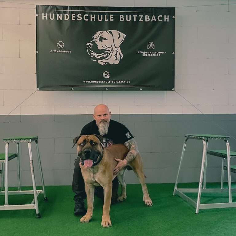 Thorsten und Odin in der Trainingshalle vor dem Banner der Hundeschule Butzbach